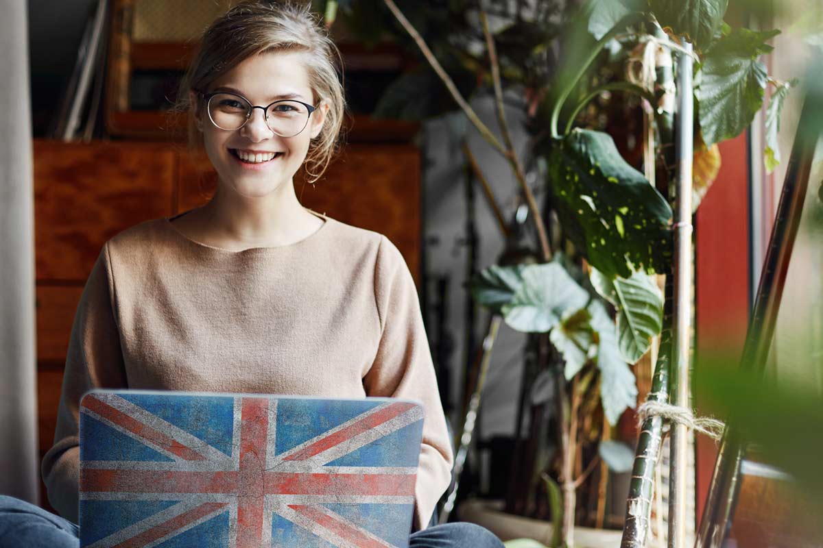 Junge Frau am Laptop m. Englischer Flagge